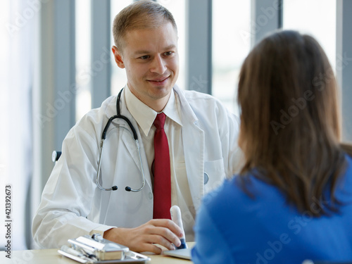 Focusing to caucasian doctor with stethoscope hang on nect look and pay attention to woman patient in examination room at hospital photo