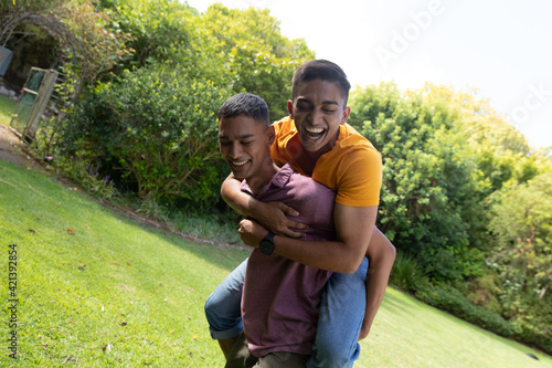 Diverse gay male couple spending time in garden embracing and smiling
