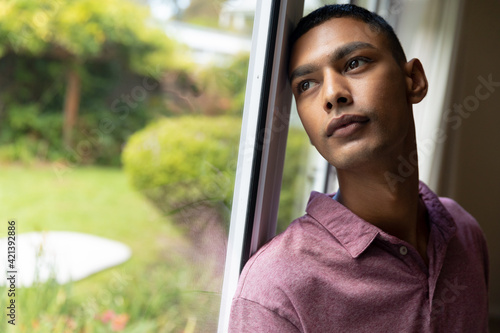 Mixed race man leaning on window and looking away