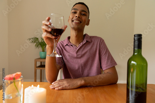 Portrait of mixed race man holding glass of red wine looking at camera smiling