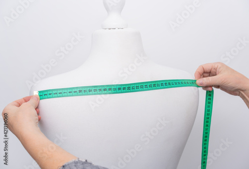 Seamstress measures the width of the shoulders on the back of a mannequin. Close up photo