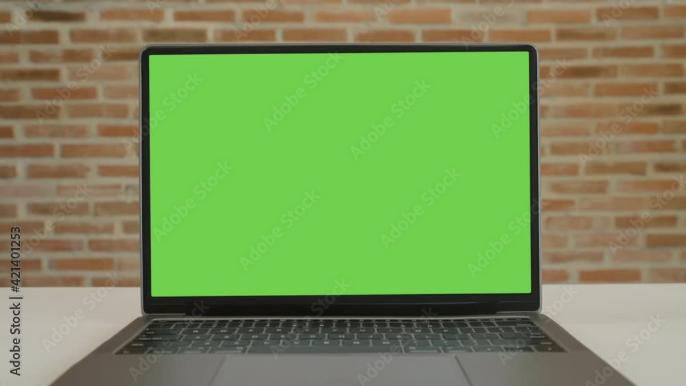 Close up display computer desktop with mock-up green screen on white table, Slow motion laptop green screen on desk and brown brick wall background, Blank of mockup notebook PC, Chroma key monitor. Close up display computer desktop with mock-up green screen on white table, Slow motion laptop green screen on desk and brown brick wall background, Blank of mockup notebook PC, Chroma key monitor.