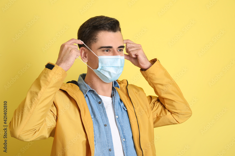 Young man wearing medical mask on color background Young man wearing medical mask on color background