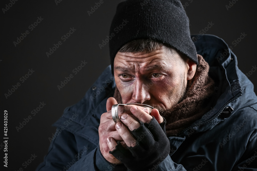 Portrait of poor homeless man with cup of hot drink on dark background Portrait of poor homeless man with cup of hot drink on dark background