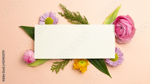 Blank memo pad with flowers on pink background. flat lay, top view, copy space