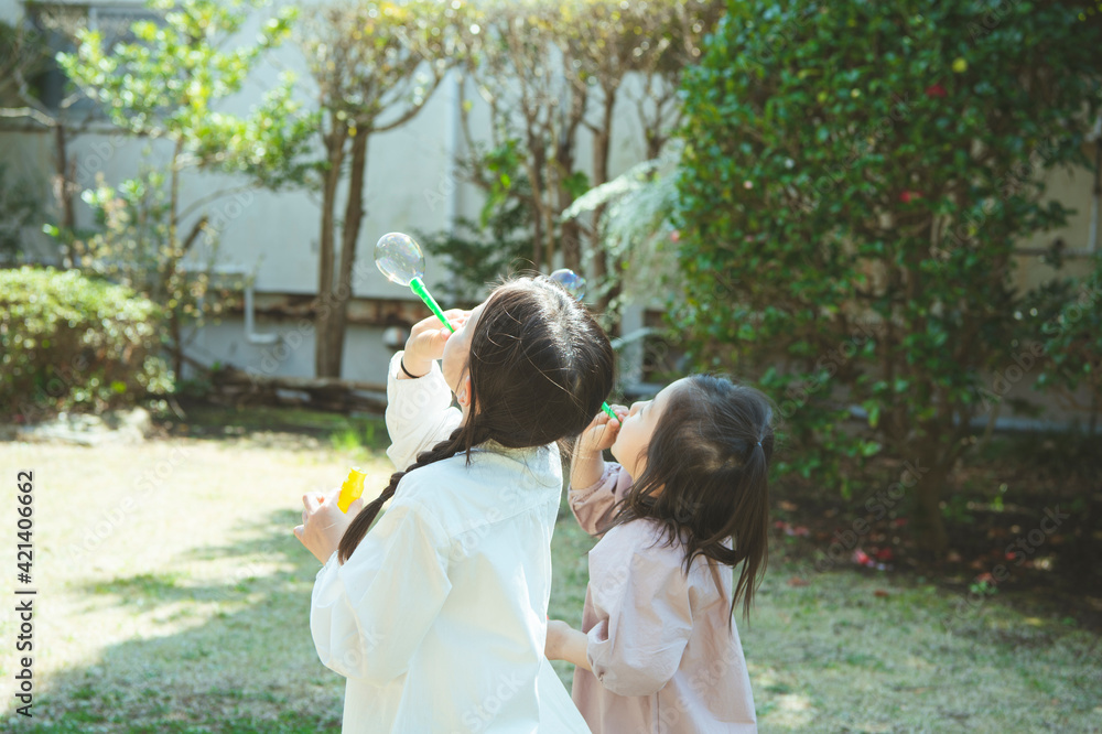 Naklejka premium シャボン玉で遊ぶ姉妹