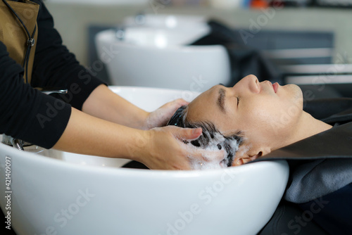 Hairdresser is applying shampoo and massaging hair of a customer. man having his hair washed in a hairdressing salon..