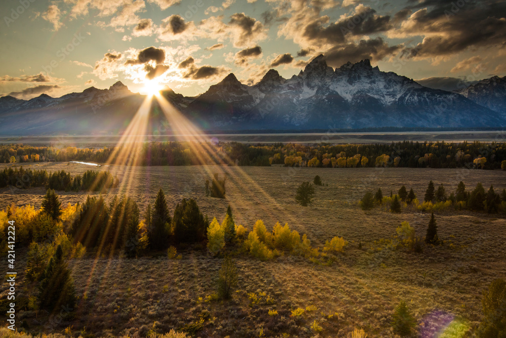 Obraz premium dramatic sunset in the snow capped peaks of the Grand Teton Mountain range and vibrant autumn colors of the trees in Jackson Hole ,Wyoming.