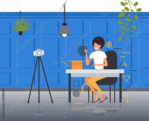 woman technology blogger opening box with headphones recording unboxing video with camera on tripod blogging live streaming concept modern office interior horizontal full length