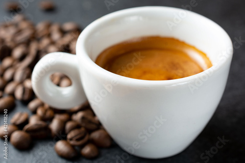 cup of coffee with fresh coffee beans on dark background