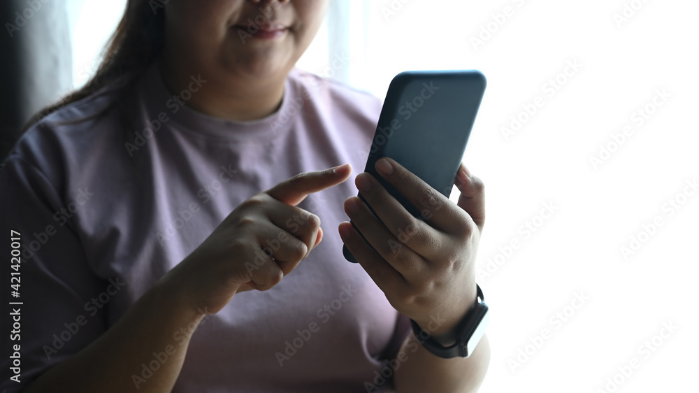 Cropped shot of happy chubby woman using smart phone at home. Cropped shot of happy chubby woman using smart phone at home.