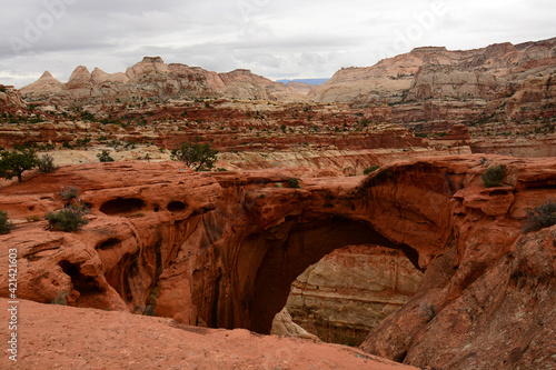 looking through cassidy's arch at the incredible eroded rock formations on a cloudy fall day in capitol reef national park, utah