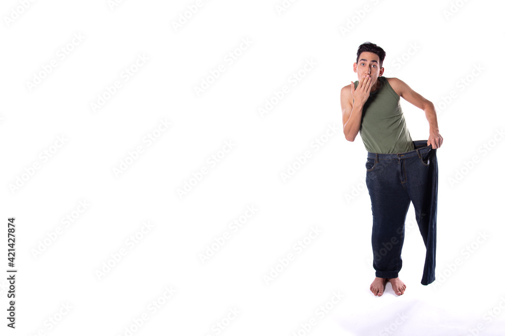 Naklejka premium Funny young guy in big pants. Diet and weight loss. The result of fitness and training. White background. Isolate.