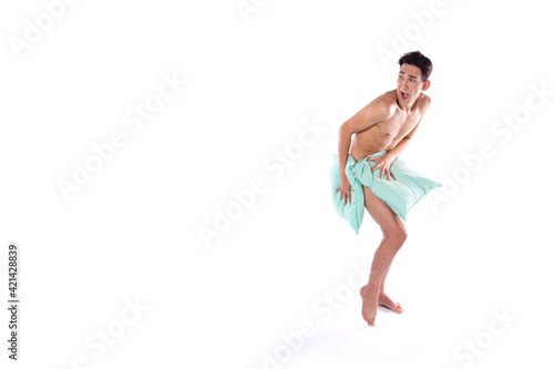 The guy is ashamed and covers himself with pillows. Beautiful body on a white background. Isolate.