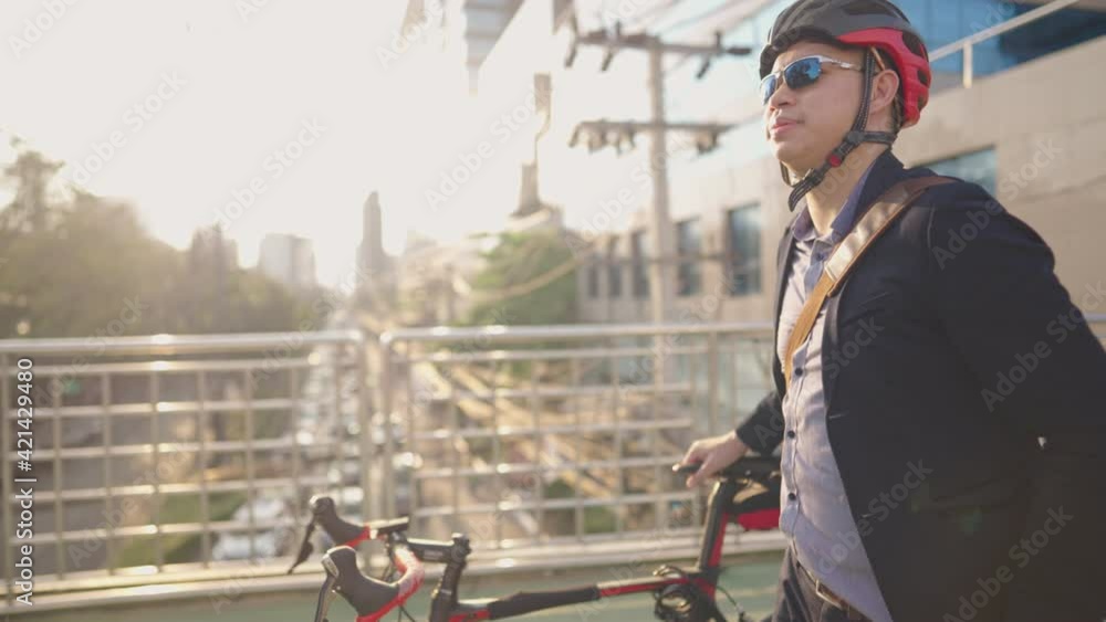 Motion of young relaxing businessman pushing his bicycle on the overpass way with carefree looking at bad traffic down there, bad traffic morning trouble solving, city lifestyle and natural saving Motion of young relaxing businessman pushing his bicycle on the overpass way with carefree looking at bad traffic down there, bad traffic morning trouble solving, city lifestyle and natural saving