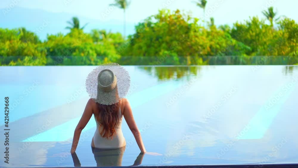 Sitting in the shallow end of a swimming pool with her back to the ...