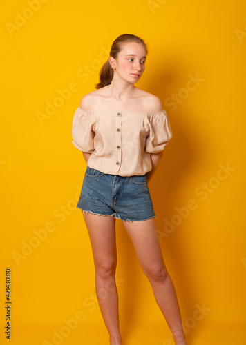 Cute teen girl wearing a fashionable shirt and denim shorts. Skinny teenage girl.
