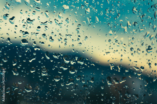 Rain drops on window glasses surface with sunset. drops on glass spray on window background for dark text  view selective focus