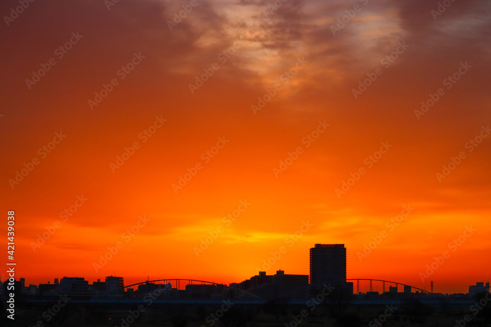 Landscape of mountains and city reflected in the orange light of sunset.