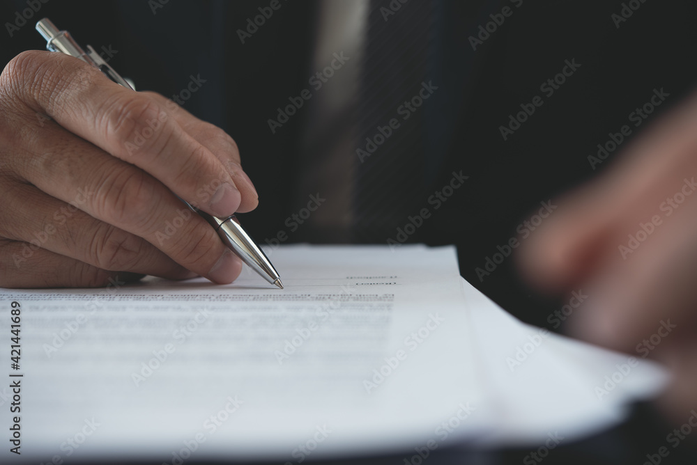 Close up of businessman hand signing business contract with a pen at office Close up of businessman hand signing business contract with a pen at office