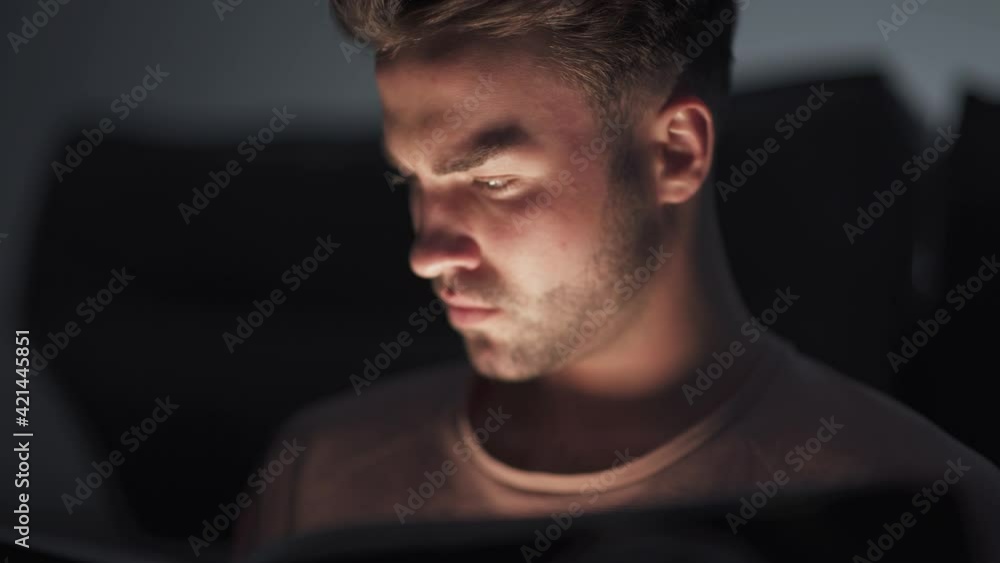 Portrait of young man sitting at home on the floor and reading a book, warm light, self-isolation during the pandemic, mystical lighting effect. Portrait of young man sitting at home on the floor and reading a book, warm light, self-isolation during the pandemic, mystical lighting effect.