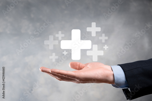 Fototapeta Naklejka Na Ścianę i Meble -  Businessman, man hold in hand offer positive thing such as profit, benefits, development, CSR represented by plus sign.The hand shows the plus sign