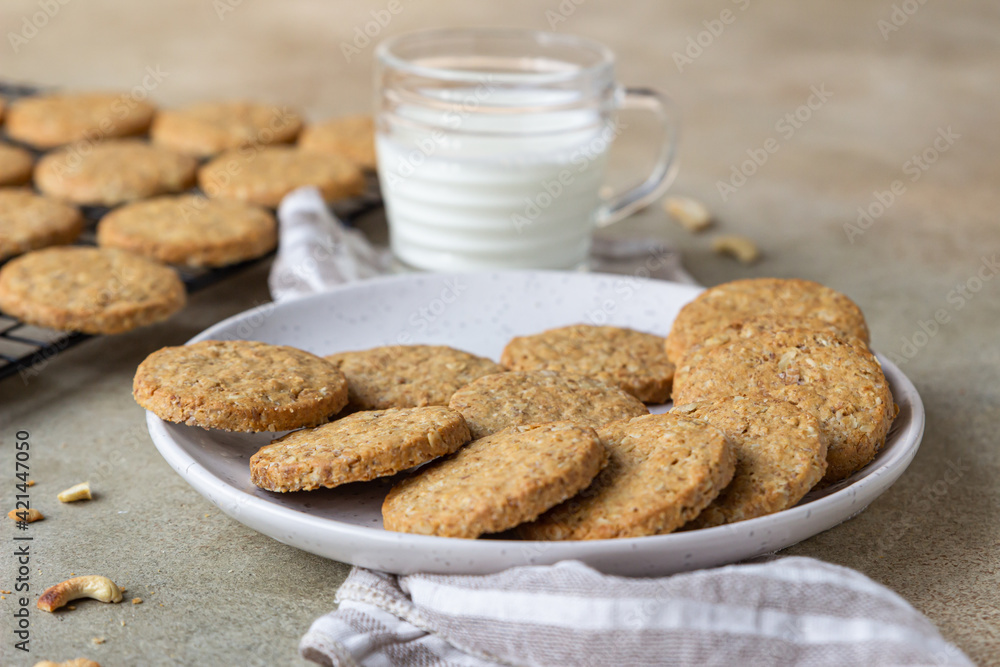 Healthy oatmeal cookies with cereals, seeds and nuts with a cup of milk on concrete background. Diet vegan cookies. Healthy oatmeal cookies with cereals, seeds and nuts with a cup of milk on concrete background. Diet vegan cookies.