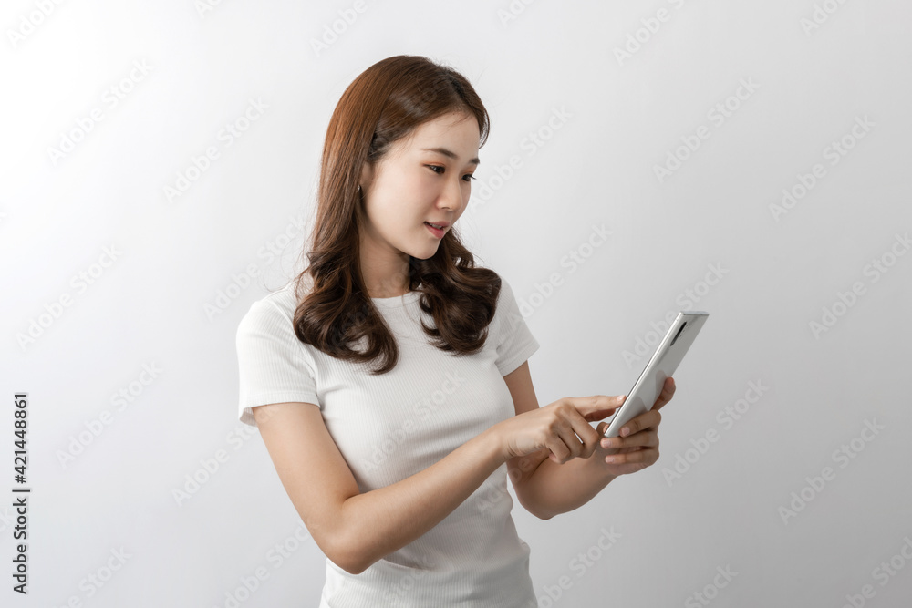 A young beautiful Asian woman with long hair smiling uses a cell phone for texting, chatting, or social media. On white background in A studio. Online technology, online shopping concept. Copy space A young beautiful Asian woman with long hair smiling uses a cell phone for texting, chatting, or social media. On white background in A studio. Online technology, online shopping concept. Copy space
