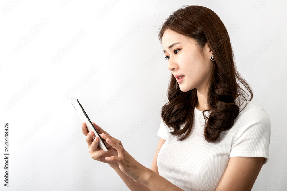 A young beautiful Asian woman looks confused on a cell phone, she is texting, chatting, or social media videos with friends. An Online technology, online shopping concept. Over white background A young beautiful Asian woman looks confused on a cell phone, she is texting, chatting, or social media videos with friends. An Online technology, online shopping concept. Over white background