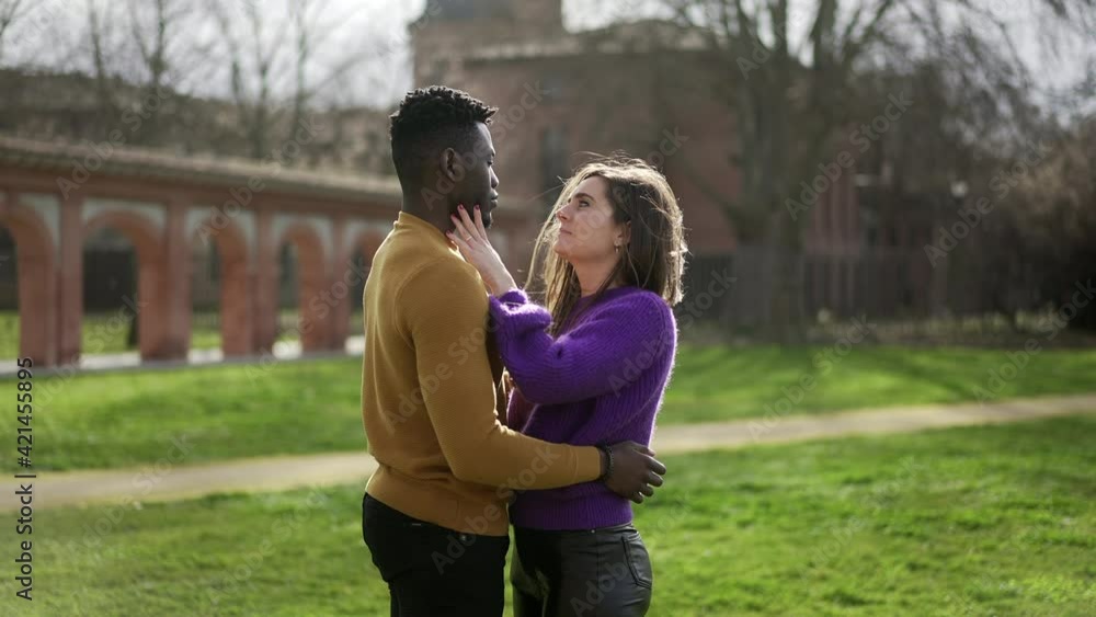 Young interracial couple love and affection standing outside at park Young interracial couple love and affection standing outside at park
