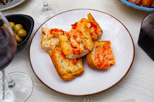 Appetizing Pan con tomate - grilled bread topped with mixture of grated tomatoes with salt and olive oil. Popular Catalan wine tapas.