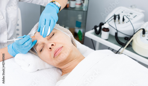 Female doctor doing beauty injection to mature woman client