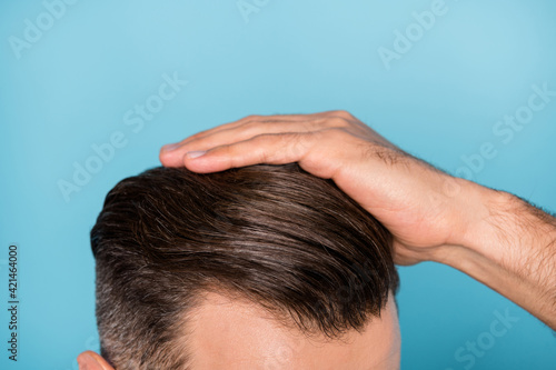 Cropped photo of young handsome man fixing his hairstyle silky healthy hair isolated on blue color background