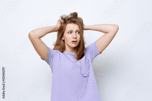 Portrait of girl in casual t shirt in panic grabbing her head in fear or frustration. Stress and mental health