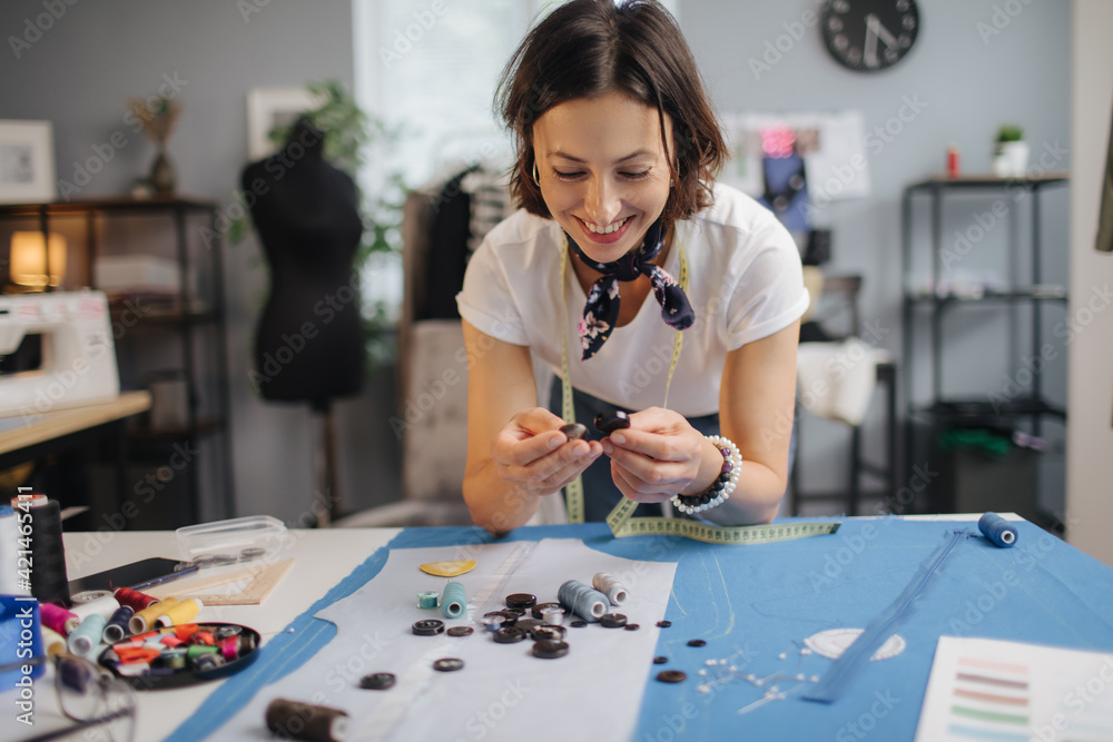 Fototapeta premium Professional designer choosing buttons for blue cloth