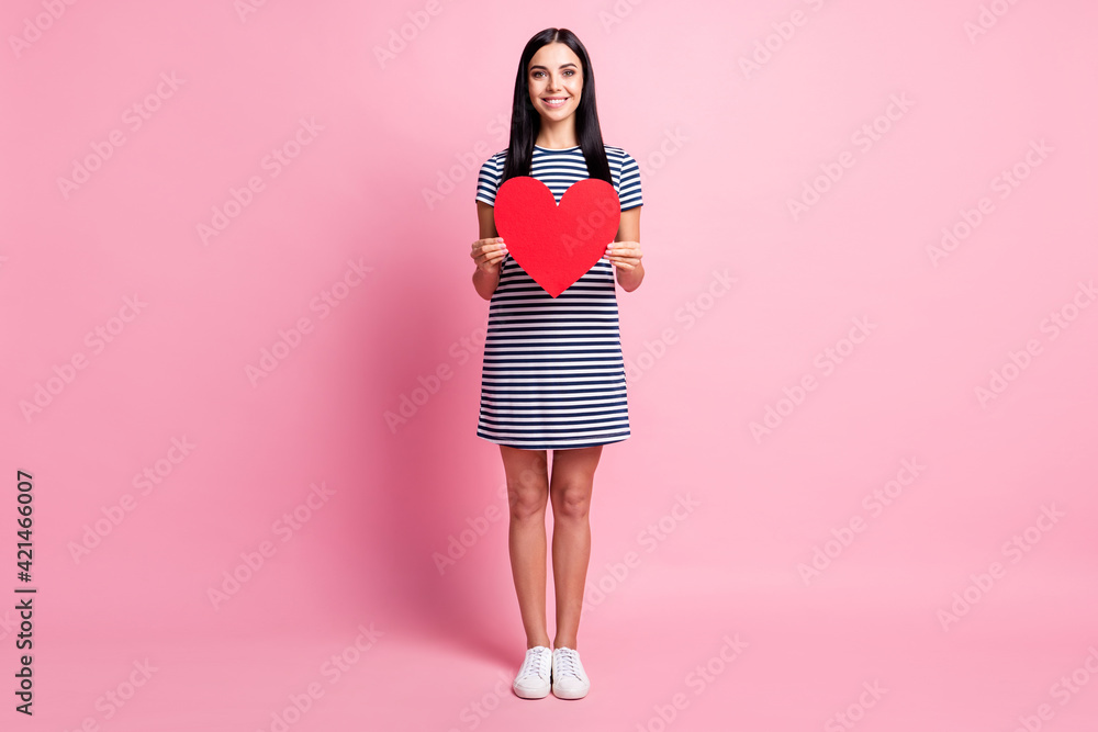 Full length body size view of pretty cheerful slim fit girl holding in hands big heart shape isolated over pink pastel color background Full length body size view of pretty cheerful slim fit girl holding in hands big heart shape isolated over pink pastel color background
