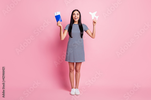 Full length body size view of lovely cheery amazed girl holding in hand plane card documents having fun isolated over pink pastel color background