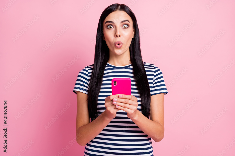 Photo portrait of impressed woman holding phone in two hands isolated on pastel pink colored background Photo portrait of impressed woman holding phone in two hands isolated on pastel pink colored background