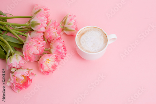 pink tulips and a cup of coffee on a pink background