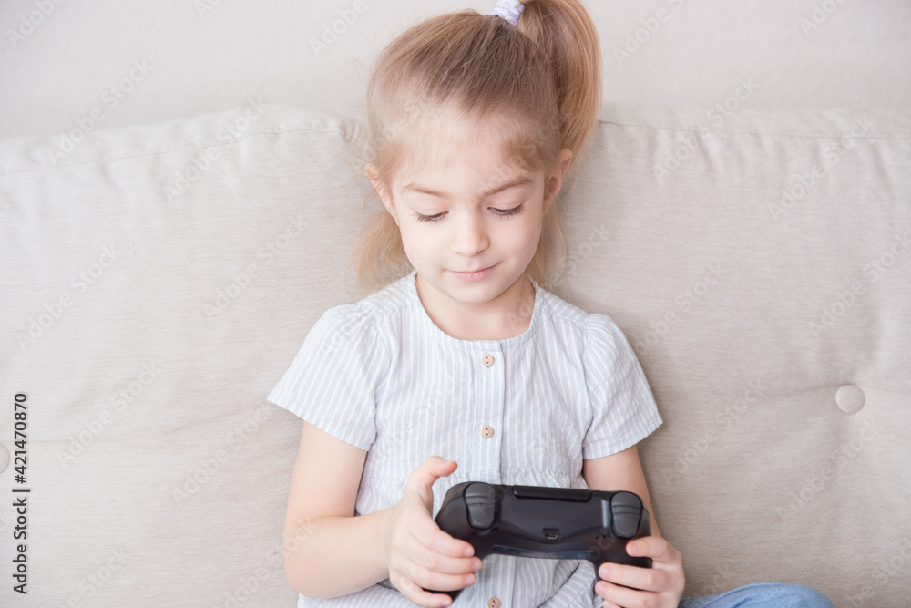 lifestyle portrait of young little girl excited and happy playing video game online holding controller having fun, kid gaming addiction. lifestyle portrait of young little girl excited and happy playing video game online holding controller having fun, kid gaming addiction.