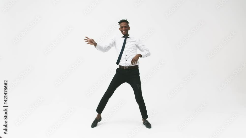 Happy black man emotionally dancing on a white background in an office suit. Young black man laughs and dances in the studio. Happy black man emotionally dancing on a white background in an office suit. Young black man laughs and dances in the studio.