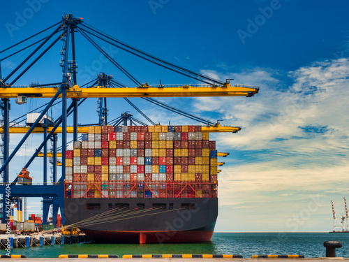 The container vessel during discharging at an industrial port and move containers to container's yard by trucks.