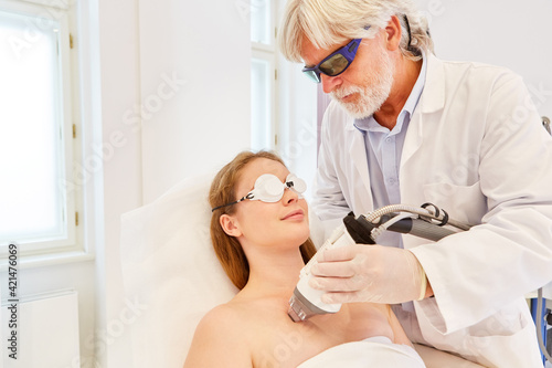 Dermatologist treats a woman's cleavage with laser photo