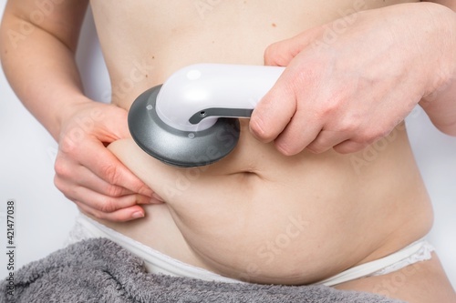 Woman massaging her belly with ultrasonic cavitation machine photo