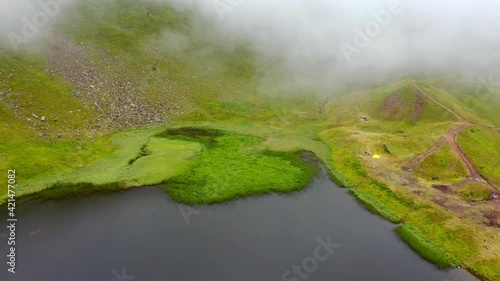 Flying through the clouds down to the ground. 4K aerial - a bird's eye view video (Ultra High Definition) of of Dohyaska lake. Beautiful morning scene of Carpathian mountains, Ukraine.. photo