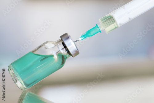 Vial filled with liquid vaccine in medical lab with syringe. medical ampoule and syringe on the glass surface