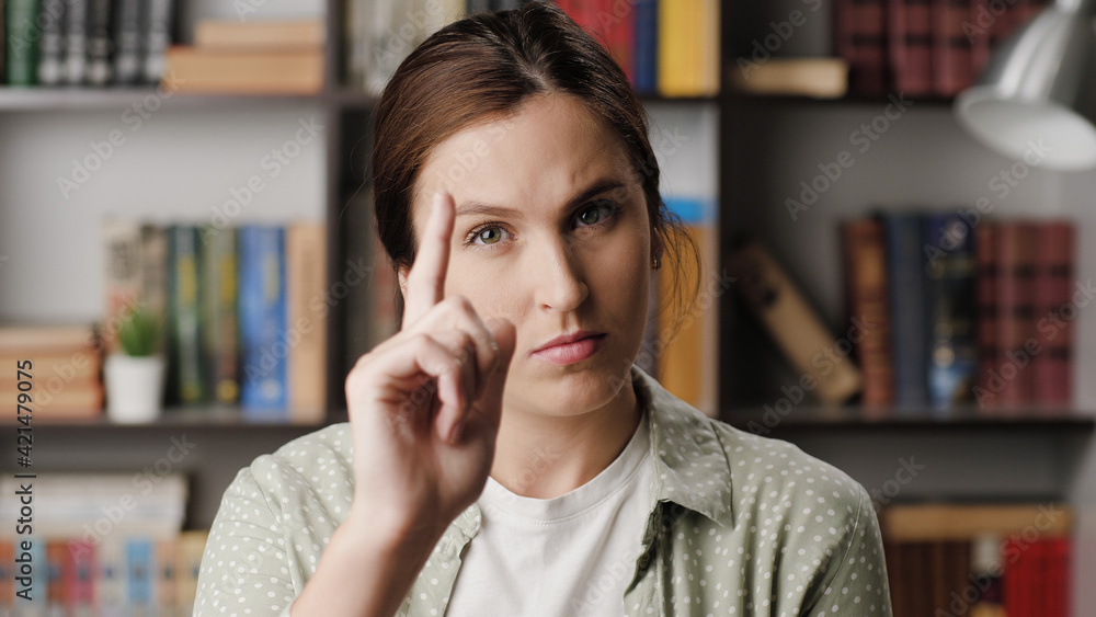Woman threatens with his finger. Serious frowning woman in office or apartment room interior looking at camera and points menacingly with her index finger. Medium shot Woman threatens with his finger. Serious frowning woman in office or apartment room interior looking at camera and points menacingly with her index finger. Medium shot