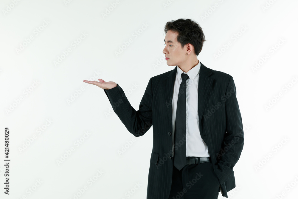 Portrait of self-confidence young and handsome Asian businessman in black suit standing and use hand present and advertising something, copy space studio shot isolated on white background Portrait of self-confidence young and handsome Asian businessman in black suit standing and use hand present and advertising something, copy space studio shot isolated on white background