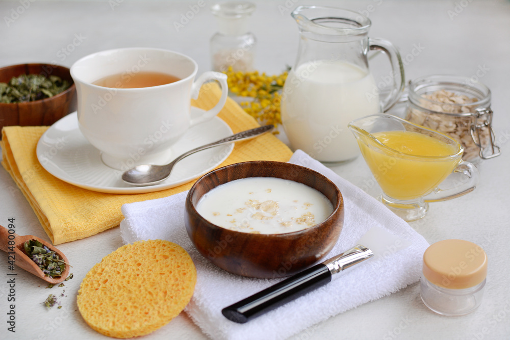The concept of beauty treatments and relaxation at home. Cup of herbal tea, face mask and ingredients for spa on light background The concept of beauty treatments and relaxation at home. Cup of herbal tea, face mask and ingredients for spa on light background