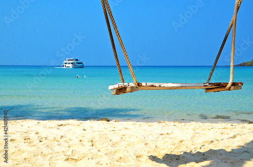 Swing on the beach. Blue sea. The big yacht sailing away